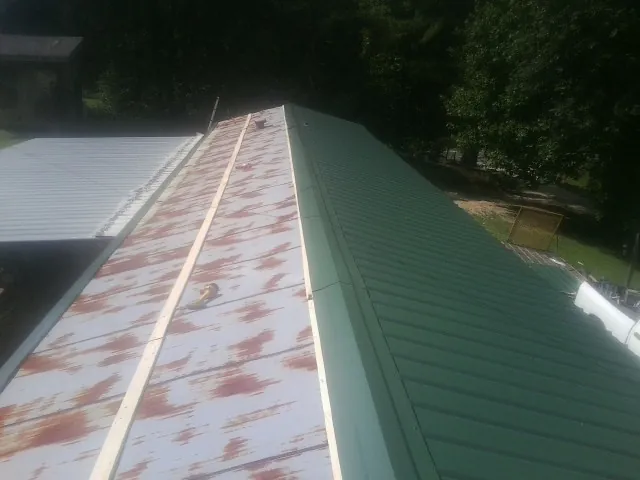 Old rusted panels beside newly installed green metal roofing — Wind Damage Roof Repair by Roofing Brothers in Lake Como