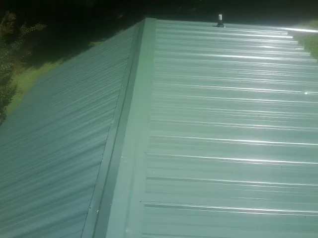 New green metal panels meeting at the ridge of a roof — Flat Roof Repair work by our crew in Lake Como