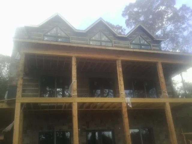 Dormers and porch framing on a large log home under construction — Roof Coating work by our crew in Lake Como