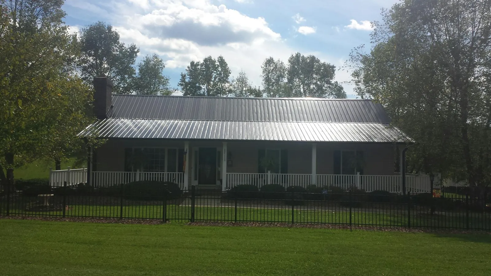Gray metal roof on a brick ranch with a full width front porch — Gutter Guard Installation work by our crew in Lake Como