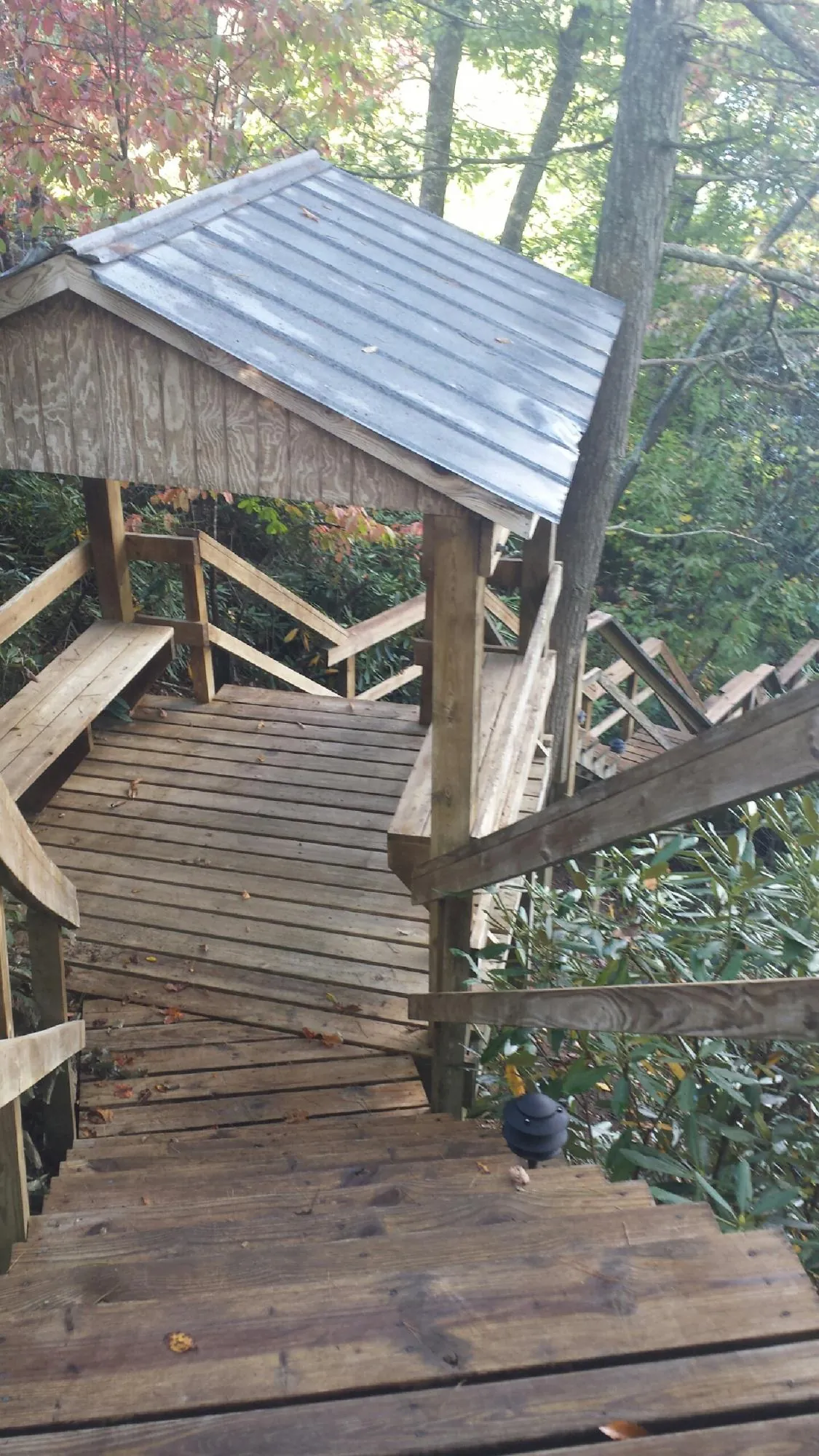 Metal roofed shelter over wooden steps on a wooded walkway — Skylight Repair & Installation work by our crew in Lake Como