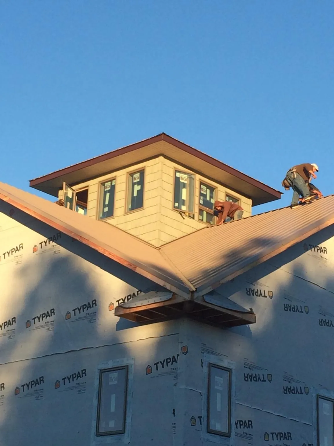 Roofers working around a rooftop cupola on a new metal roof at sunset — Roof Waterproofing in Lake Como by Roofing Brothers